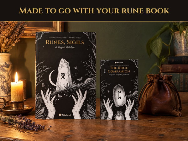 The Rune Companion standing beside Runes, Sigils & Magical Alphabets on a wooden table with a candle and a leather rune pouch, showing the pocket size next to the full book